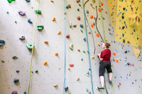 Foto einer Frau, die an einer Kletterwand klettert