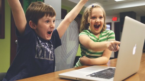 Foto: Jubende Kinder schauen auf einen Laptop-Bildschirm