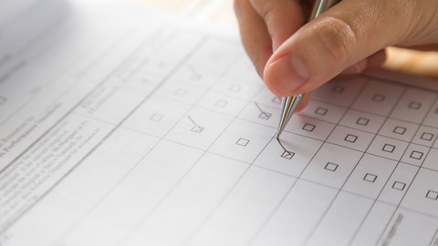 Hand, die einen Fragebogen ausfüllt