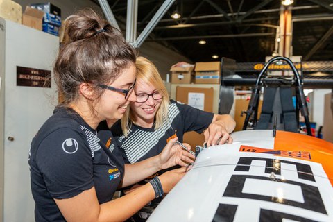 Zwei junge Frauen arbeiten an einem Fahrzueg