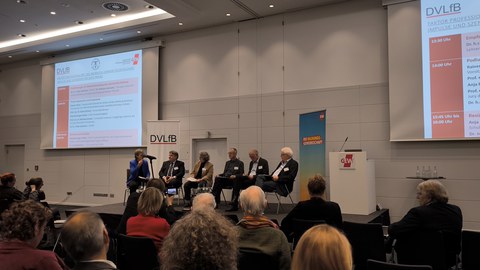 Podiumsdiskussion mit sechs Diskutierenden auf einer Bühne