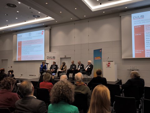 Podiumsdiskussion mit sechs Diskutierenden auf einer Bühne