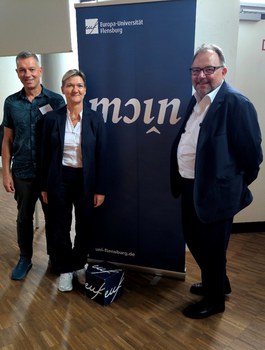 Gruppenbild mit 3 Personen vor einem Roll Up