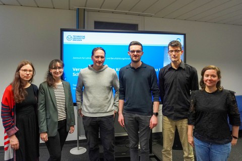 Gruppenfoto mit 6 Personen vor einem vor einem BIldschirm mit Titelfolie einer Präsentation