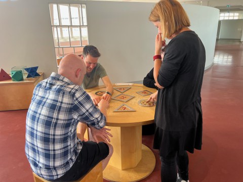 3 Personen lösen ein Puzzle namens "Pferch"