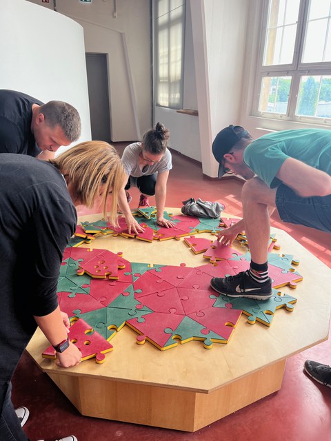 Vier Personen spielen an einem großen Puzzle