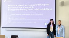 Zwei Frauen stehen vor einer Beamerleinwand, die eine Titelfolie einer Präsentation zeigt
