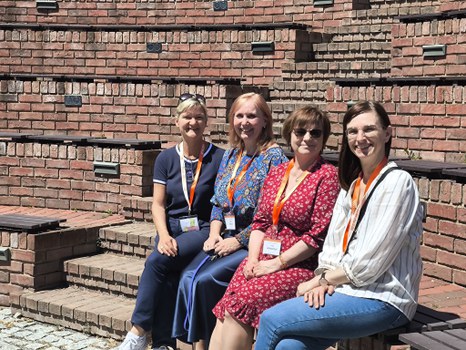 4 Frauen sitzen nebeneinander auf Stufen eines Amphitheaters