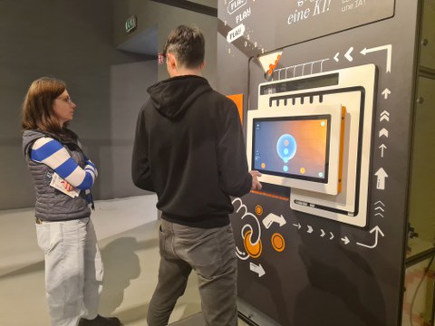 Mann und Frau stehen in einem Museum vor einem Bildschirm, welcher als Exponat dient.