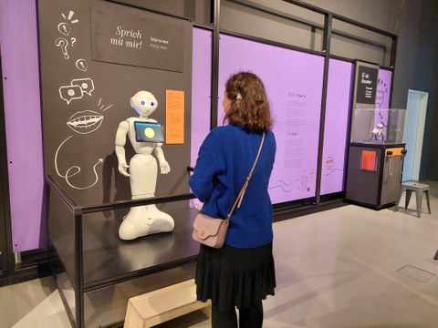 Frau steht vor einem kleinen humanoiden Roboter