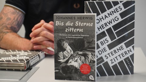 Nahaufnahme von zwei Büchern mit dem Autor im Hintergrund