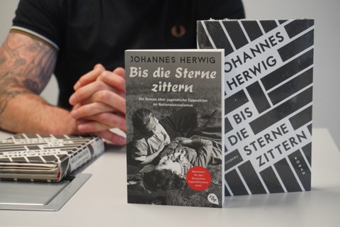 Nahaufnahme von zwei Büchern mit dem Autor im Hintergrund