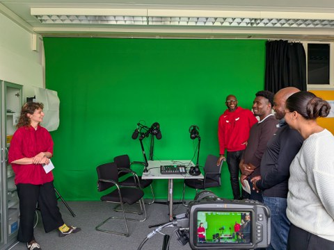 Junge Frau erklärt mehreren Personen GreenScreen Technik in einem Medienlabor