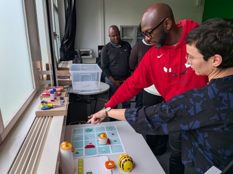 Frau erklärt Mann spielerische Lehr-Lern-Werkzeuge zur informatischen Bildung