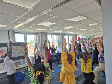 Gruppe von Personen, die in einer Lernwerkstatt zusammen Yoga ausüben.