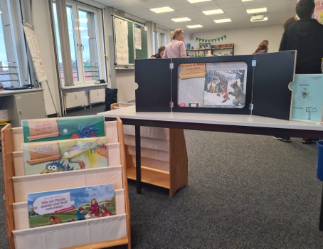 Mini Theater Aufbau auf einem Tisch und Kinderbücher in einem Regal.