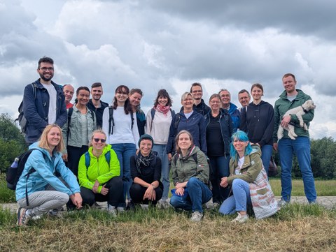 Gruppenbild mit ca. 20 Personen im Freien auf einer Wiese bei grauem Wetter