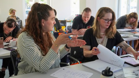 Zwei Frauen, die nebeneinander in einem Seminar sitzen. 