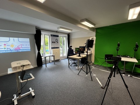 Man sieht ein Panorama des Medienlabor am ZLSB der TU Dresden: Im Raum mit der Greenscreen-Wand sind Kameras, Miros, PCs, Bildschirme und Beamer aufgebaut.