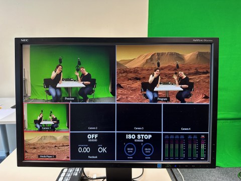 Auf diesem Bild sieht man an einem Bildschirm, wie in Echtzeit bei einer Videoszene mittels Greenscreen-Technik der Hintergrund ausgetauscht wird.