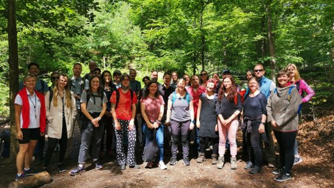 Gruppenbild von ca. 30 Erwachsenen in einem Wald
