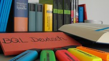 Bücher des Deutschunterrichtes vor denen verschieden farbige Filzstifte liegen.