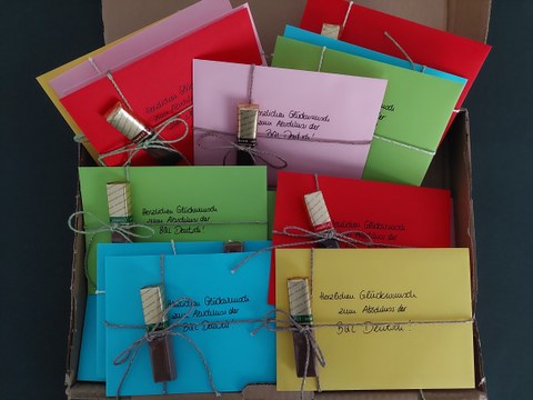 Zu sehen sind bunte Abschiedsgeschenke, in Form von bunten Briefumschlägen mit Schokolade drangebunden, von der Feierlichen Verabschiedung im Fach BQL-Deutsch