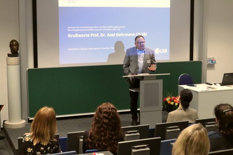 Auf dem Bild ist Herr Prof. Dr. Gehrmann (Geschäftsführender Direktor ZLSB) bei der feierlichen Verabschiedung zu sehen, wie er eine Rede im Hörsaal an der DIU hält.