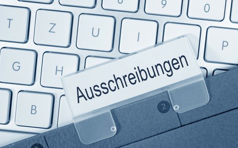 Foto zeigt eine Tastatur, auf der ein Ordner liegt zum Thema "Ausschreibungen".